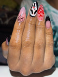 Hand with creatively designed nails featuring Halloween-themed patterns.