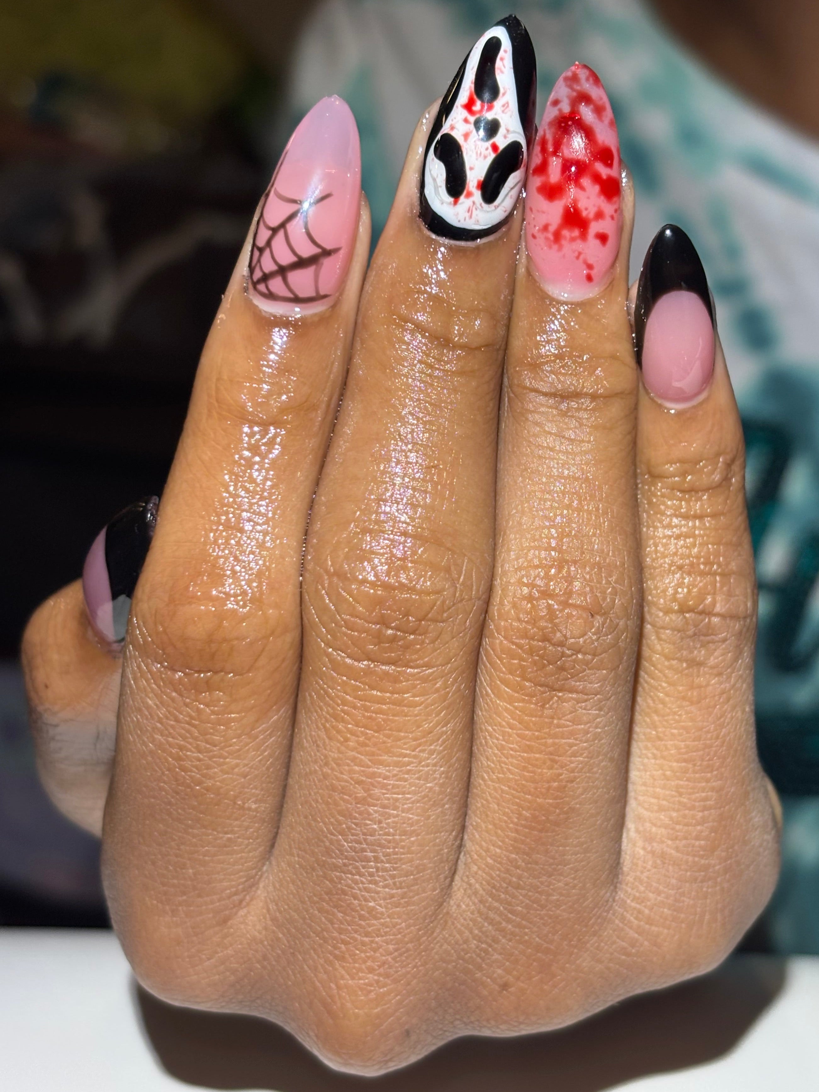 Hand with creatively designed nails featuring Halloween-themed patterns.